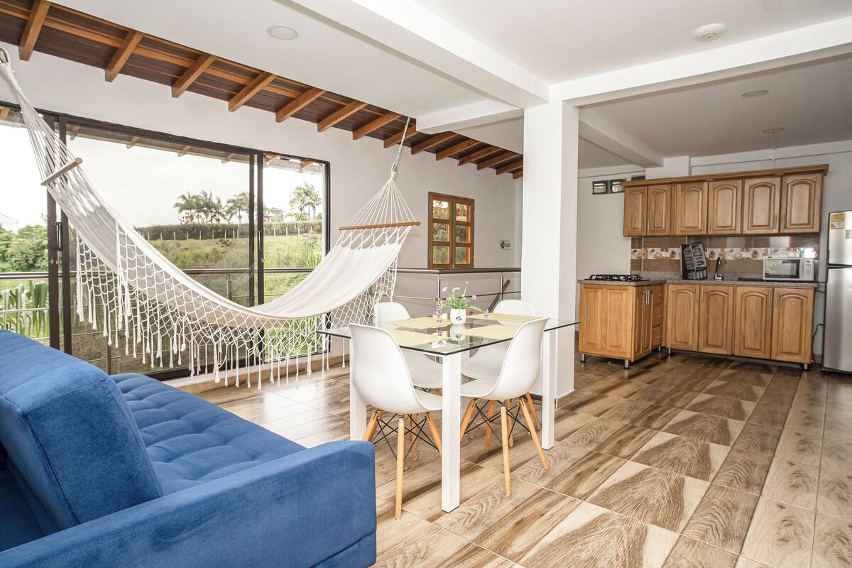 Una cucina moderna con mobili in legno, un tavolo da pranzo con sedie e un'amaca.