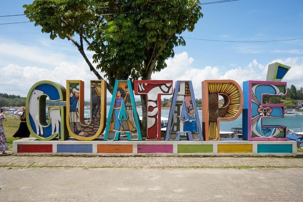 Un letrero colorido con la palabra “GUATAPÉ” y diversas figuras artísticas.