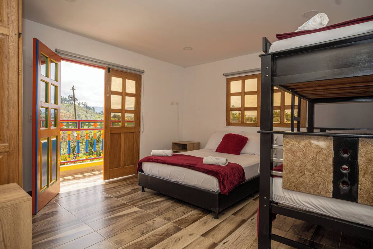 Una camera da letto con un letto a castello, una porta in legno che dà su un balcone e vista sull'esterno.