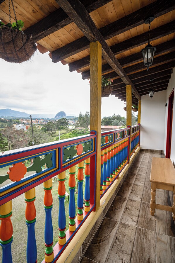 A balcony with colorful railings, a hanging plant, and a wooden table. - ROBLE COLONIAL  (Guatape)
