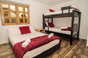 A room with two bunk beds, a wooden floor, a window with a view, and a red blanket on the lower bed. - ROBLE COLONIAL  (Guatape)