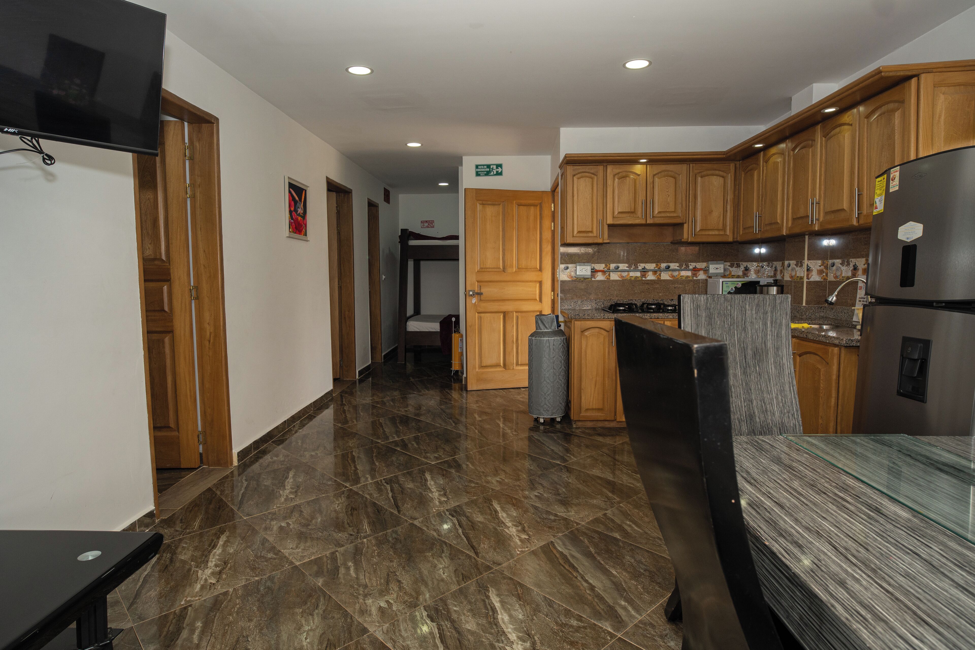 Una cocina moderna con armarios de madera, un refrigerador de acero inoxidable y una mesa de comedor con cubierta de vidrio.