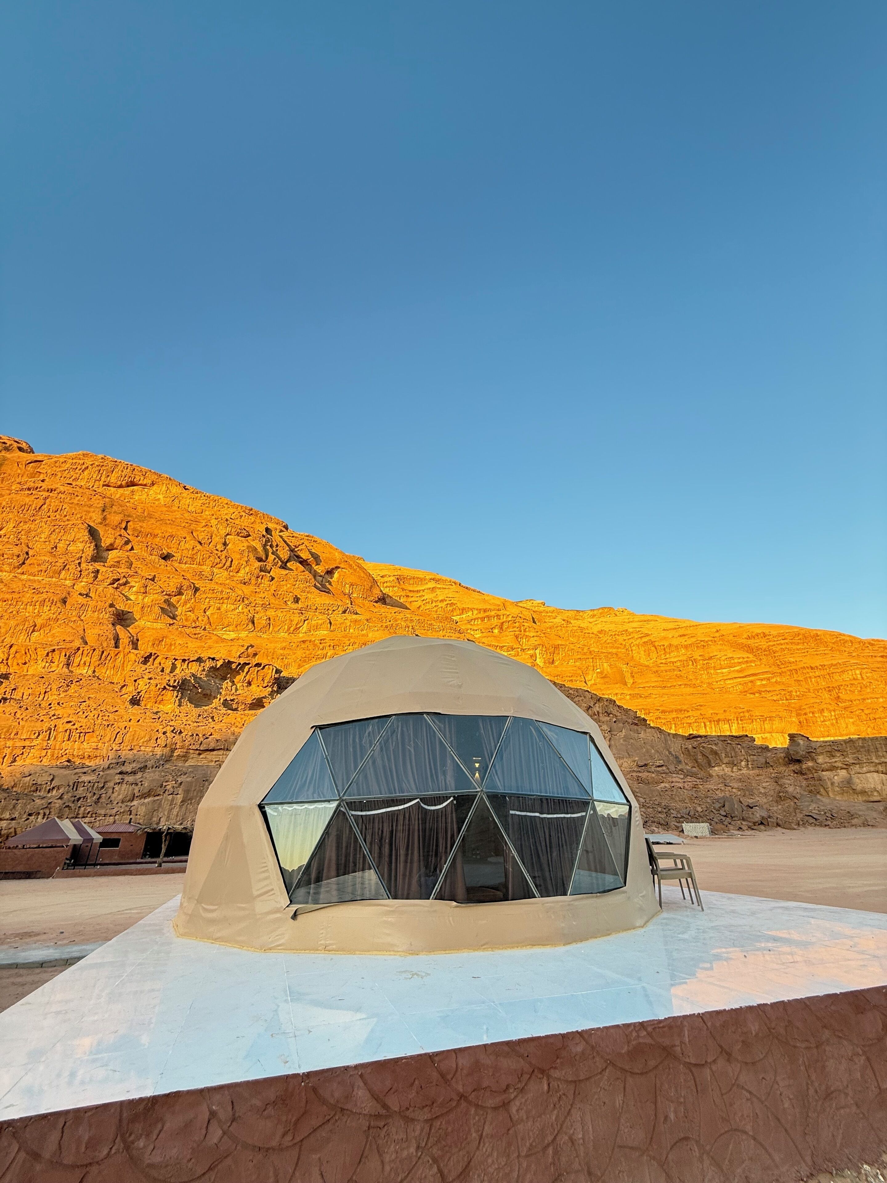 Una tenda a cupola geodetica con vista libera sul paesaggio desertico circostante e sulle montagne.