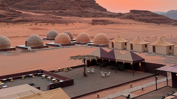 A desert resort with dome-shaped tents and a terrace area with tables and chairs. - Arjowana Luxury Camp (Wadi Rum)