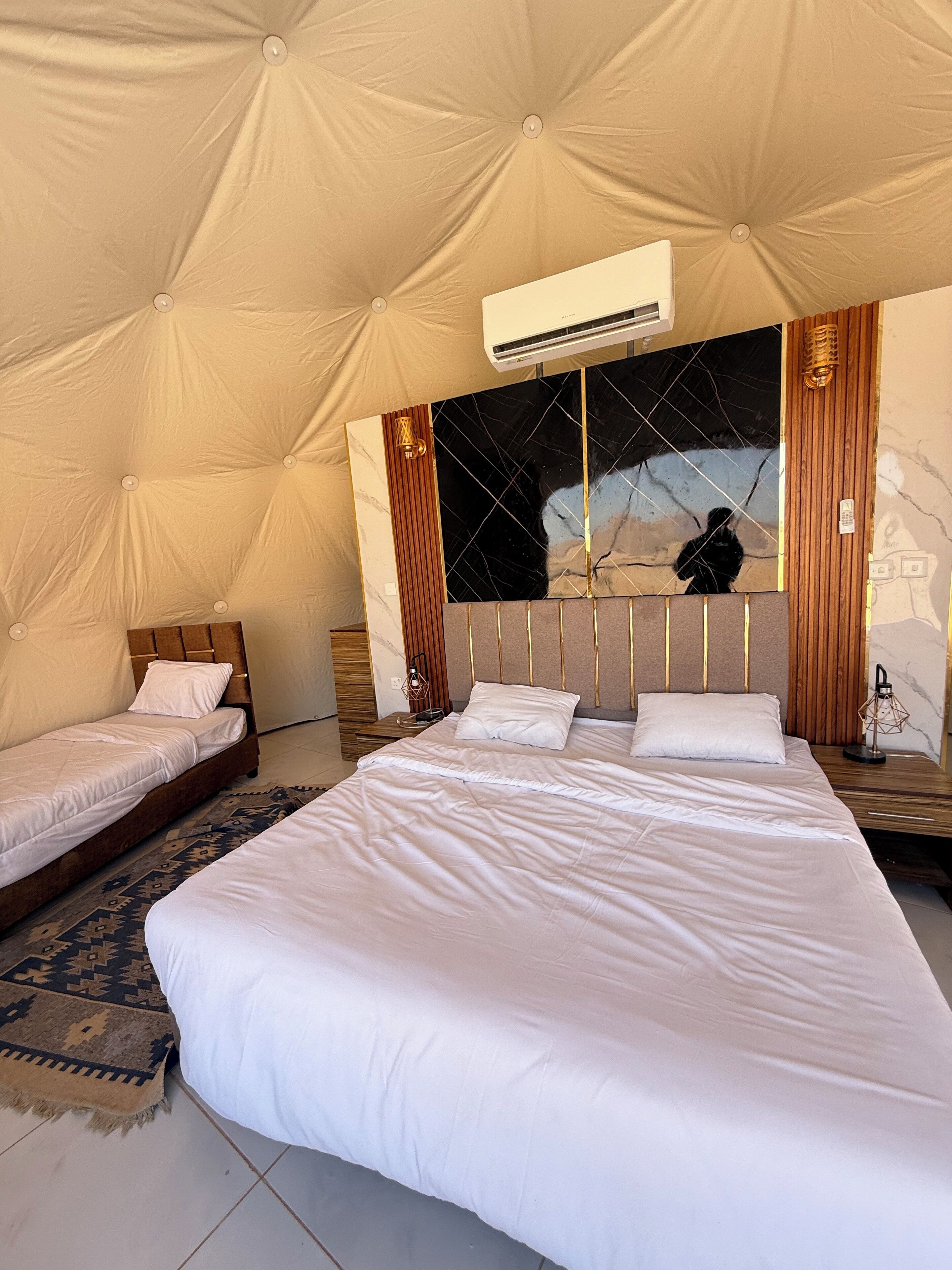 A spacious tent-style room with two beds, a large mirror, and an air conditioning unit.