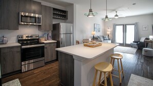 A modern kitchen with stainless steel appliances, wooden cabinets, and a central island with stools.