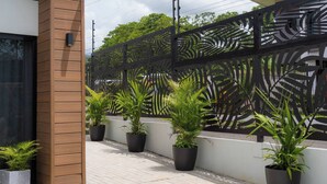 A modern outdoor area with a wooden column, a decorative metal fence, and potted plants. - Sakura Haus (Turrialba)