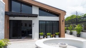 A modern building with a large glass entrance, a circular outdoor seating area, and potted plants. - Sakura Haus (Turrialba)