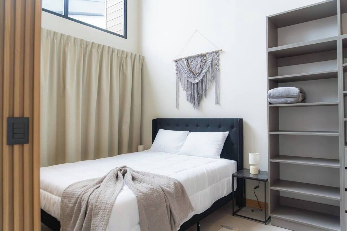A neatly arranged bedroom with a bed, bedside table, and a large wardrobe.
