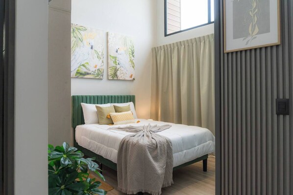 Ein Schlafzimmer mit einem Bett, einem grünen Kopfteil und zwei an der Wand befestigten Bildern.