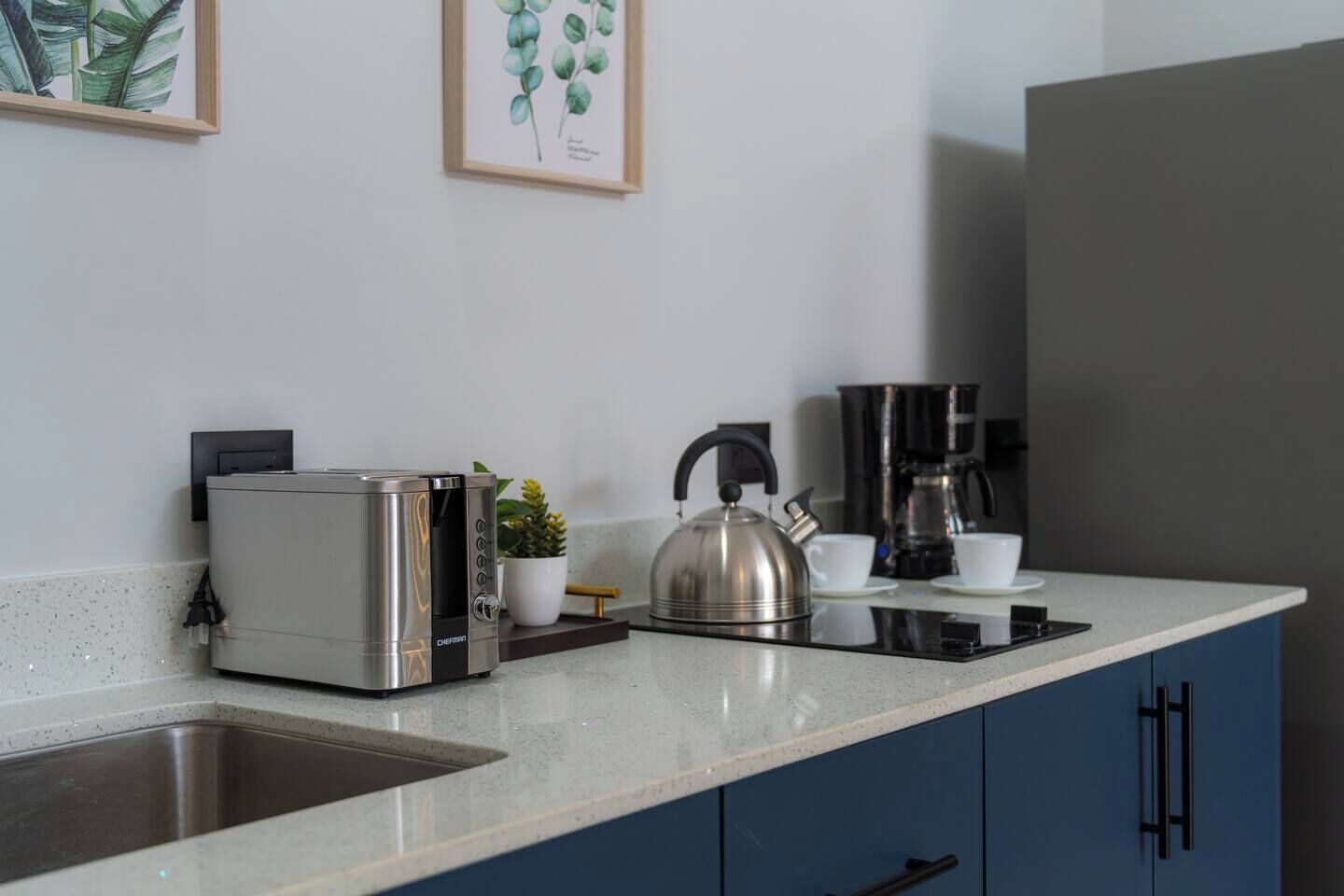 A modern kitchen with a built-in toaster, kettle, and coffee maker on a countertop.