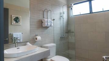 Un baño moderno con lavamanos, inodoro y ducha con mampara de vidrio.