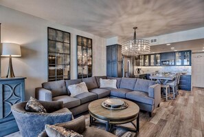 A modern living room with a sectional sofa, a round coffee table, and a chandelier.