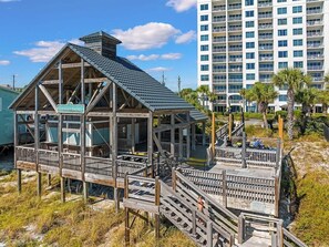 A beachfront hotel with a wooden deck structure and a sign reading 'Emerald Shores.' - Leeward Key # 504 | Gulf Views + Pool & Elevator! (Miramar Beach)