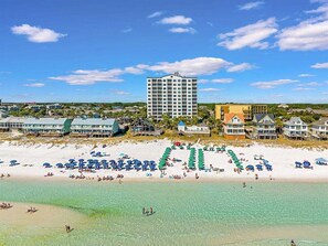 A coastal hotel with a beachfront, multiple swimming pools, and a large building in the background. - Leeward Key # 504 | Gulf Views + Pool & Elevator! (Miramar Beach)