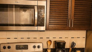 Una cocina con estufa, microondas y armarios de madera.