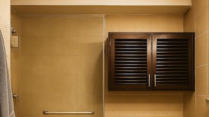 Un baño con ducha, inodoro y armarios de madera oscura.