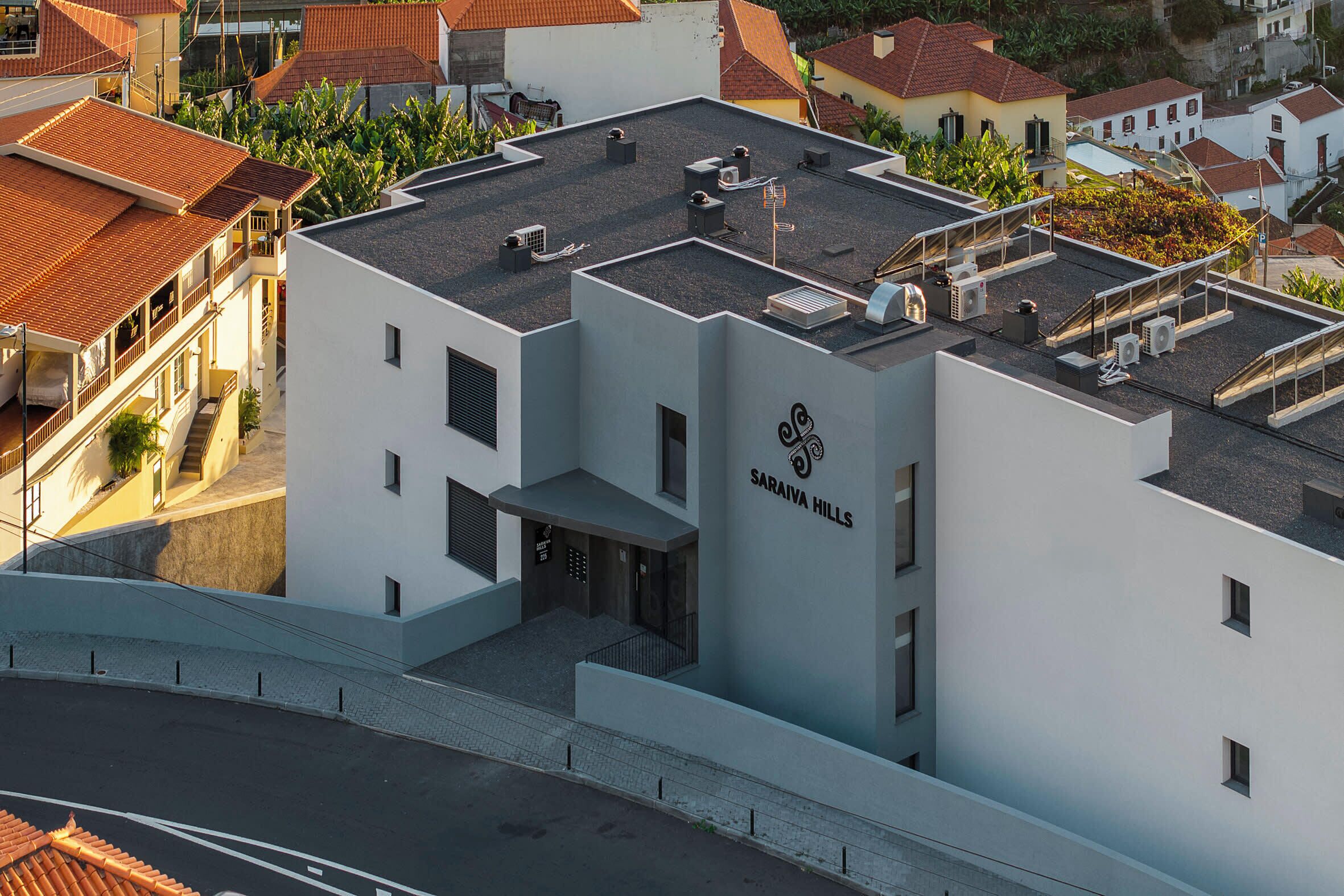 Een modern gebouw met een plat dak en airconditioners, met een bord waarop 'Saraiya Hills' staat.