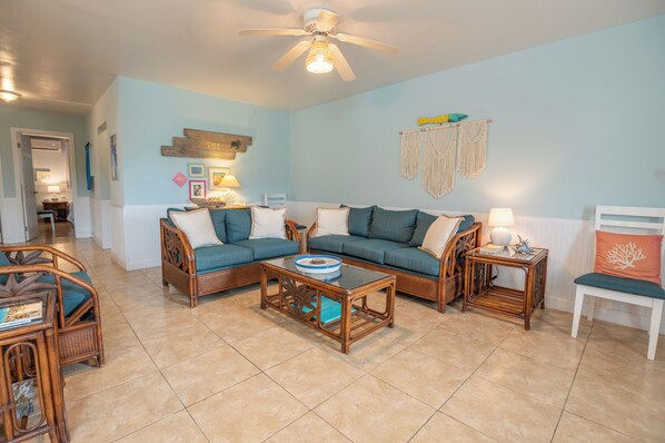 A living room with a sofa set, a coffee table, and a ceiling fan.