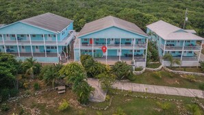 Ein Küstenhotel mit drei blauen Gebäuden, jedes mit mehreren Balkonen und einem Innenhof.