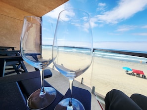 Dos copas de vino vacías sobre una mesa con vista a la playa y el océano.