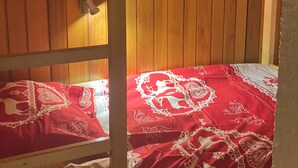 A bunk bed with a red patterned bedspread and a white pillow.