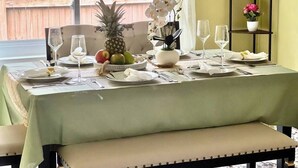 Una mesa de comedor dispuesta con platos, vasos y una piña como centro de mesa.