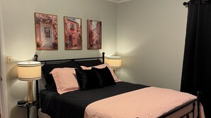 Un dormitorio con una cama, dos lámparas de noche, una mesita de noche y tres cuadros en la pared.