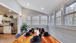 A dining area with a long wooden table set for a meal, surrounded by white walls and large windows. - Pocono Retreat 4BR, Hot Tub,Game Room,  (Long Pond)