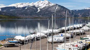 Una marina con barche ormeggiate, un lago calmo e montagne innevate sullo sfondo.