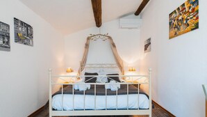 Een slaapkamer met een bed met wit metalen frame, een hemelbed en twee bedlampjes.