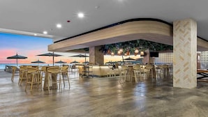 Un espace bar moderne avec un plancher en bois, des tabourets de bar et des parasols.