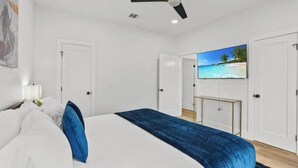A bedroom with a bed, a ceiling fan, a TV on the wall, and a door. - ACL Ready ! ~ Near Downtown & Airport ~ Backyard! (Austin)
