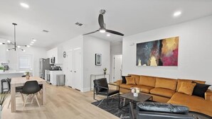 Een moderne woonkamer met een bank, salontafel en een eethoek.