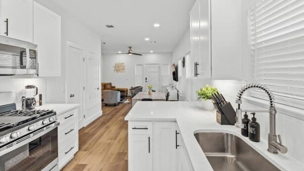 Une cuisine moderne avec des meubles blancs, un évier en acier inoxydable et un îlot central.