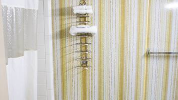 A bathroom with a toilet, a shower curtain, a toilet paper holder, and a towel rack.