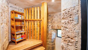 Une pièce rustique avec une bibliothèque en bois, des murs en pierre et une petite fenêtre.