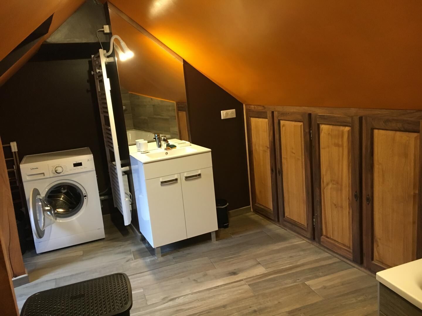 A compact laundry room with a washing machine, a sink, and wooden cabinets.