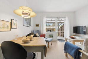 A modern living room with a dining area, a TV, and a large window with a view.