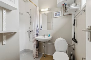 Ein Badezimmer mit Dusche, Waschbecken, Toilette und Handtuchhalter.