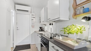 A compact kitchen with white cabinetry, a built-in oven, a sink, and a countertop with a plant. - Holiday bliss by forest and Bornholm’s top beach (Nexø)