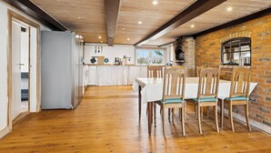 Eine moderne Küche mit Holzböden, einer Backsteinwand und einem Essbereich mit Holzsesseln.