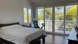 Un dormitorio con una cama grande, una cinta de correr y un balcón con vistas a zonas verdes.