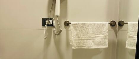 A bathroom with a white sink, a towel rack with two towels, a hairdryer, and a mirror.