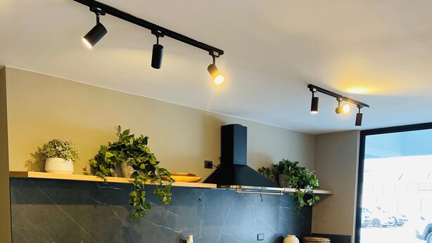 Una cocina moderna con encimera de mármol, armarios de madera e iluminación debajo de los armarios.