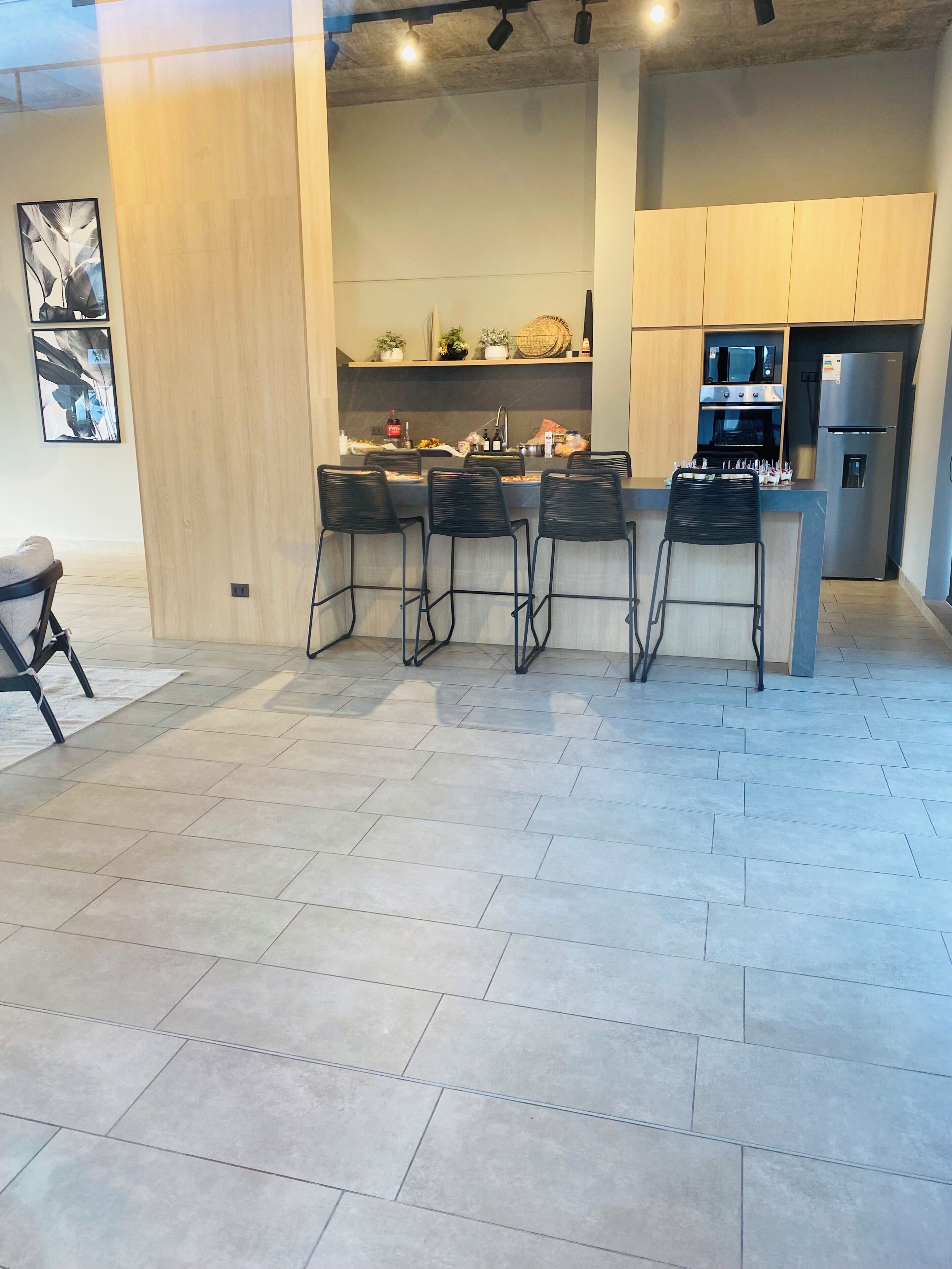 A modern kitchen with a central island, bar stools, a refrigerator, and an oven.