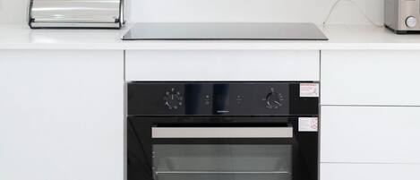 A kitchen with a built-in oven, a toaster, and a range hood.