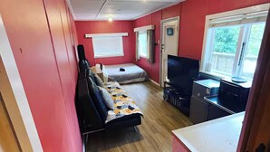 Ein kleines Zimmer mit Bett, Schreibtisch, Fernseher und Fenster.