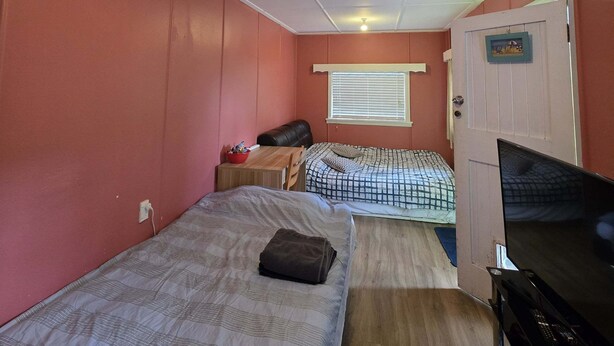 A compact room with two beds, a television, and a small table with a red bowl. - Lifestyle farm stay retreat near CBD (Wainuiomata)