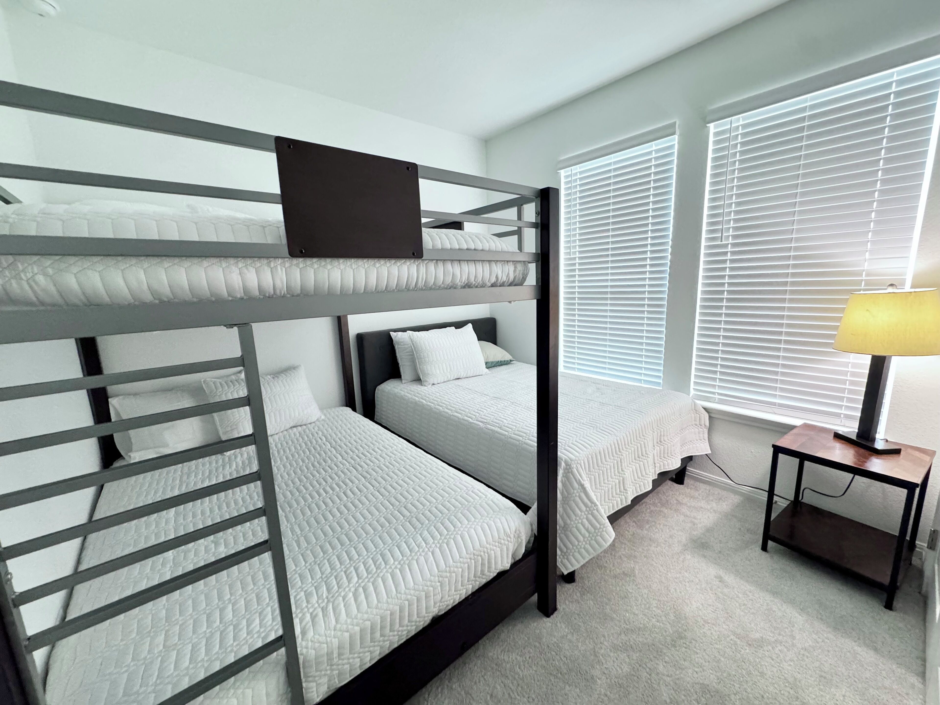 A bunk bed room with a desk and lamp.